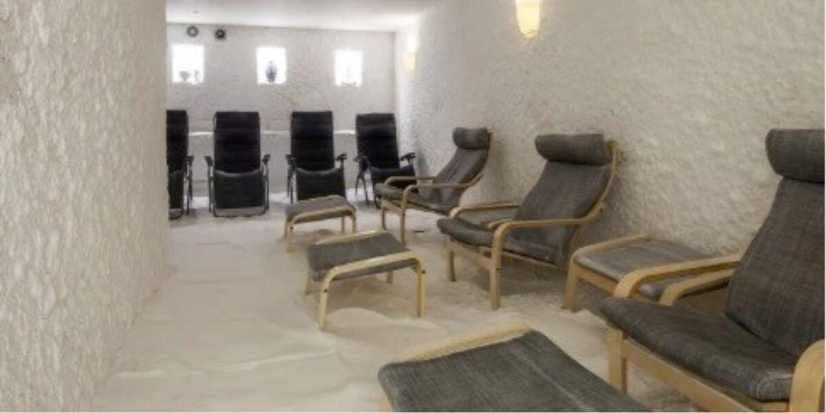 A serene salt room with white textured walls and floor at HaloClinic Nederland